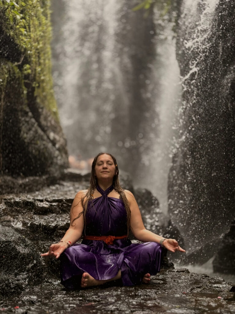 Woman in white participating in Melukat purification ritual at sacred Balinese water temple Ubud