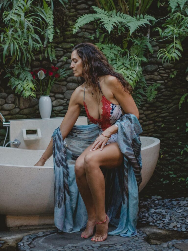 Radiant solo woman soaking in tropical flower bath at private luxury villa in Ubud Bali wellness retreat